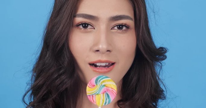 Asian beautiful woman tasting candy sweet and happy emotion smile. beautiful woman feeling sweet sugar. Concept of beauty, food, fashion, travel and shopping.