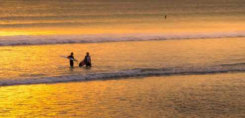 Fototapeta na wymiar two surfers walking in after having surfed at kuta beach, bali