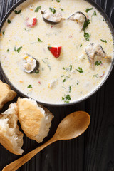 Cream eel soup with vegetables close-up in a bowl. Vertical top view