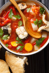 Vegetable soup with eel fish and tomatoes closeup in a bowl. Vertical top view