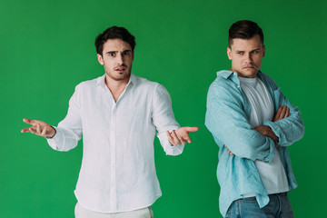 two offended men in shirts isolated on green