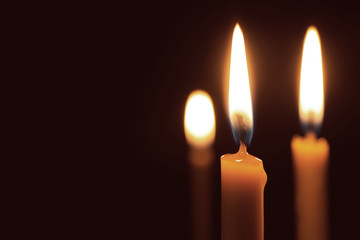 Burning candles on dark background, space for text. Symbol of sorrow