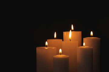Burning candles on dark background, space for text. Symbol of sorrow