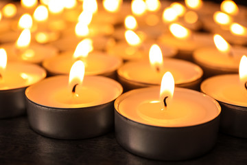 Many burning candles on table, closeup. Symbol of sorrow