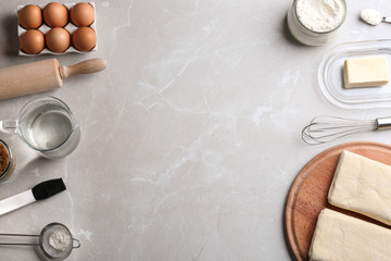 Frame made with puff pastry dough and ingredients on grey table, flat lay. Space for text