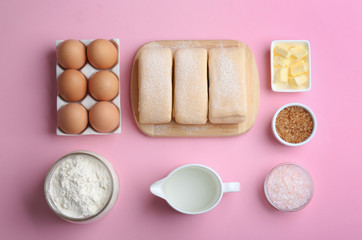Flat lay composition of puff pastry dough and ingredients on pink background