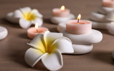 Spa stones, flowers and burning candles on wooden table