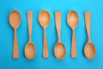 Clean empty wooden spoons on blue background, flat lay