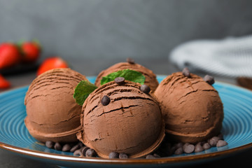 Plate of chocolate ice cream with mint on grey table, closeup. Space for text