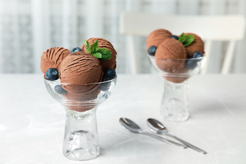 Glass bowls of chocolate ice cream and blueberries served on light table. Space for text