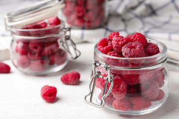 Jar of delicious fresh ripe raspberries on white wooden table, closeup view. Space for text