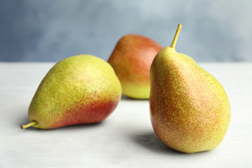 Ripe juicy pears on white wooden table against blue background