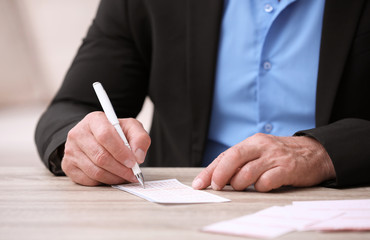 Senior man filling out lottery ticket at table, closeup