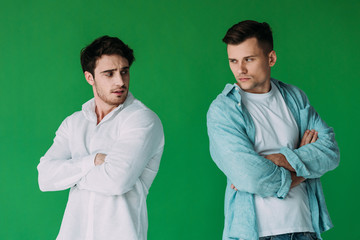 two offended men in shirts standing with crossed arms isolated on green