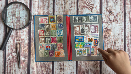 girl looking postage stamps with a magnifying glass, top view