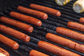 hotdogs on an outdoor girl with corn on the cob