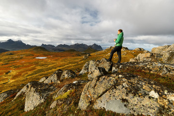 Man holding a cup of coffee with golden landscapes in the background on Lofoten Islands