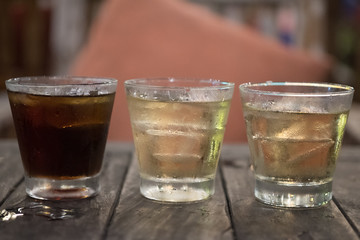 Three of iced drink on wood table in night pub.