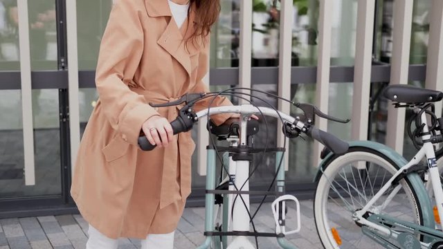 A young woman walks over to the bike and inspects it.