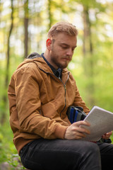 Obraz premium One young man, looking in papers in a notebook. Sitting in fores