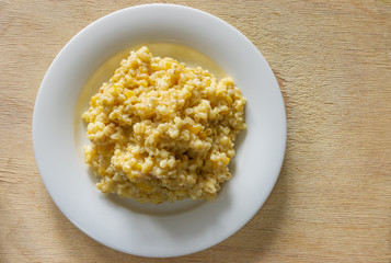 Top view on white plate  with bulgur cooked in milk with pieces of pumpkin