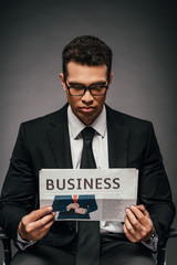 african american businessman reading business newspaper on dark background