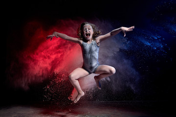 Small jumping girl during photoshoot with flour in dark studio