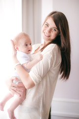 family, child and parenthood concept - happy smiling young mother with little baby at home