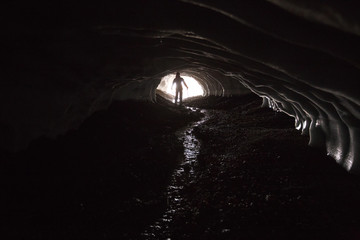 Silhouette of a man in the ice tunnel. Light from behind. Landmannalaugar trek, ice cave, Iceland