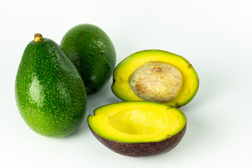 Green fresh ripe whole Avocado and cut in half, organic tropical smooth oily fruit, stone and pulp are visible isolated on white background.