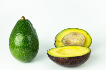 Green fresh ripe whole Avocado and cut in half, organic tropical smooth oily fruit, stone and pulp are visible isolated on white background.