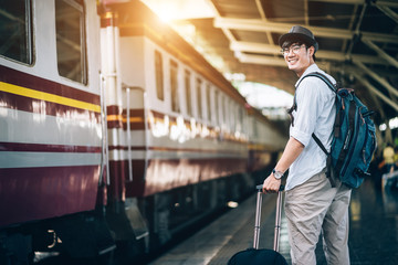 Fototapeta na wymiar Asian man is traveler, he is waiting for their train. Outdoor adventure travel by train concept. Bangkok, Thailand. Happy/positive/healthy hike/travel/wanderlust concept