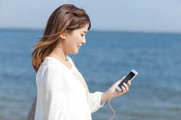 海辺で音楽を聴く女性