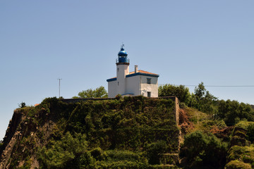 Fototapeta na wymiar Faro blanco y azul en lo alto de un acantilado. 
