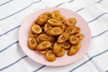 Homemade fried plantains on a pink plate, low angle view. Close-up.