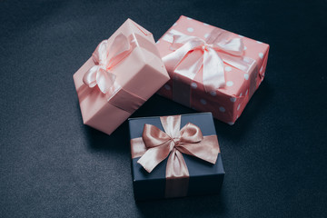 beautiful gift boxes wrapped in paper with red, gold and pink ribbon on a black surface. Top view with copy space.