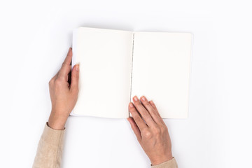 Obraz premium Woman's hands with perfect manicure holding notepad as mockup for your design. White background, flat lay style.