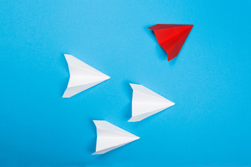 Group of white paper plane in one direction and one red paper plane pointing in different way on blue background. Business for innovative