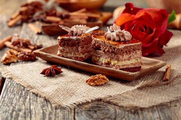Layered cakes with spices and nuts on a old wooden table.