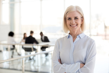 Head shot portrait smiling mature businesswoman posing in office hallway