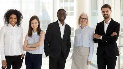 Portrait of diverse smiling team employees standing in row in office
