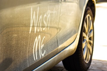 Write the words "wash me" on the very dirty surface of the car. Concept car wash.