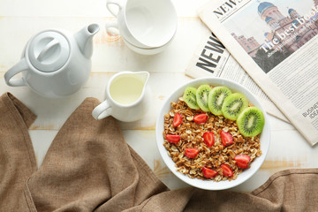 Bowl with tasty sweet oatmeal, milk in jug and teapot on table