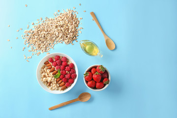 Bowl with tasty sweet oatmeal, honey and berries on color background