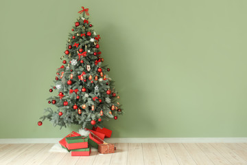 Beautiful decorated Christmas tree near color wall