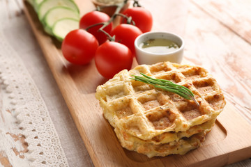 Tasty squash waffles with vegetables on wooden board