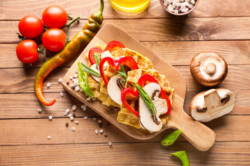Composition with tasty squash waffles and vegetables on wooden table