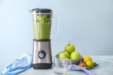 Blender with healthy smoothie and ingredients on table
