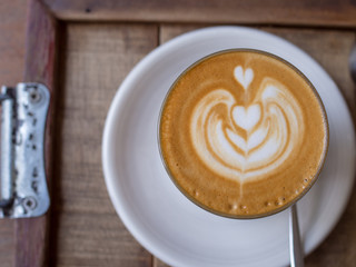 Coffee art with heart-shape pattern in cup on wooden table in the garden, Close up cup of coffee coffee with heart-shape pattern.Copy Space