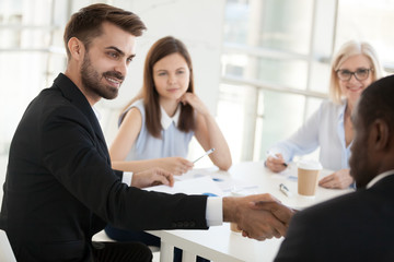 Confident businessman shaking hand colleague at company meeting